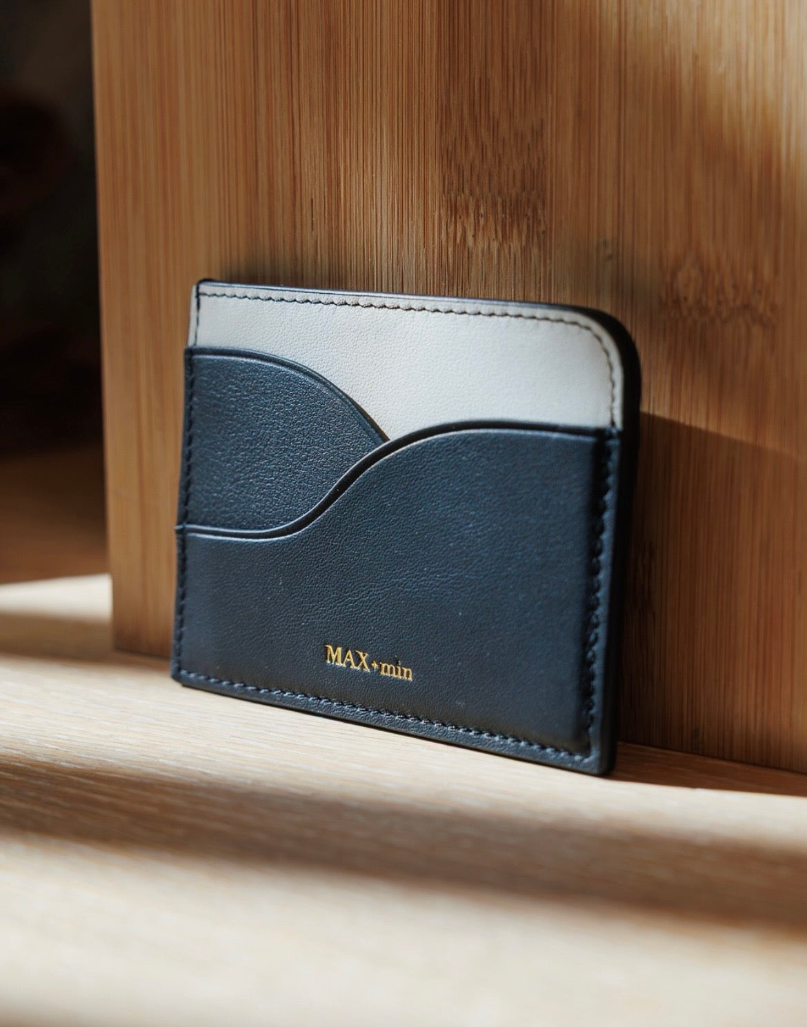 MAX+min black leather card holder shown with cards for scale.