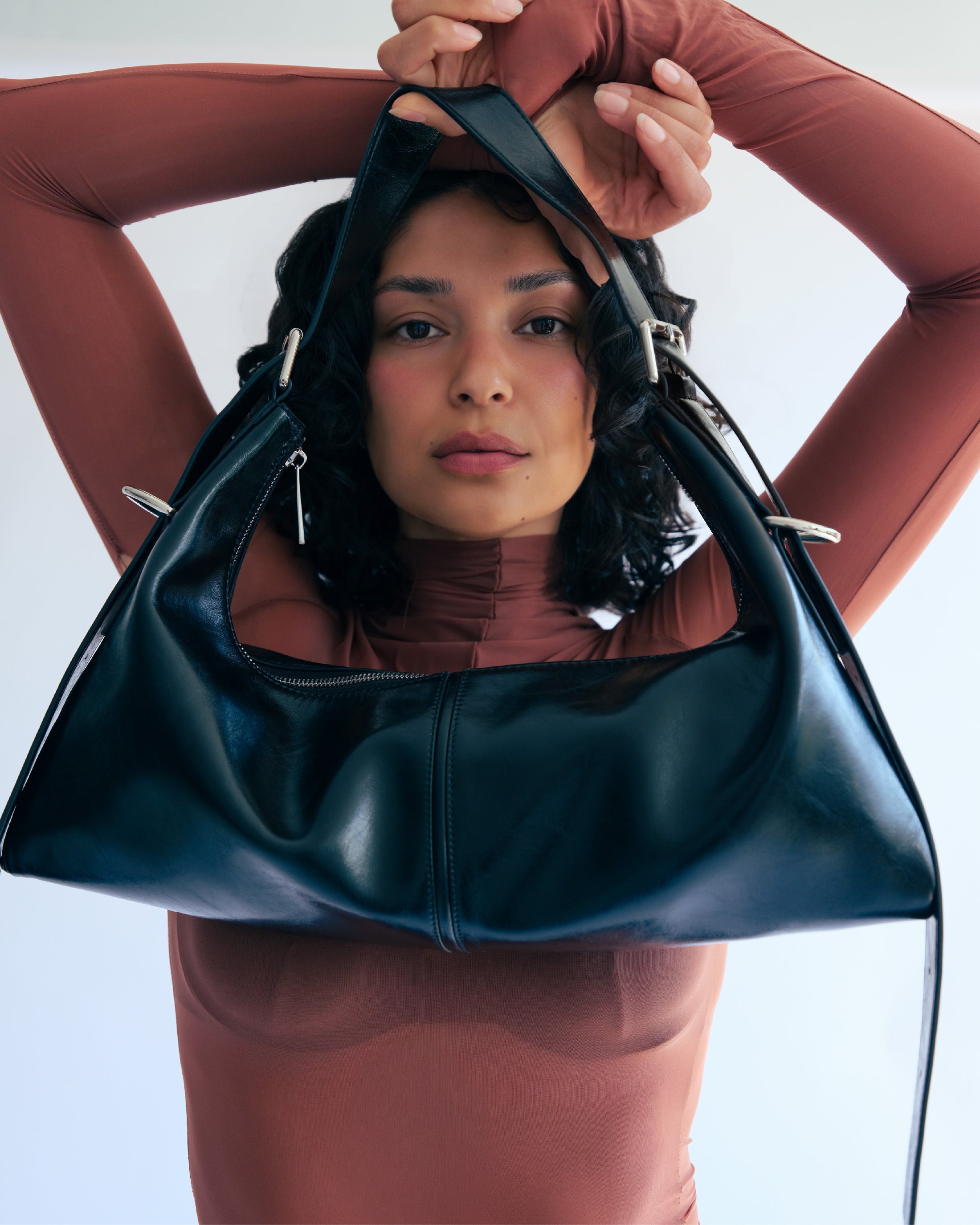 MAX+min Maximum Bag in black leather, shown with convertible strap styling.